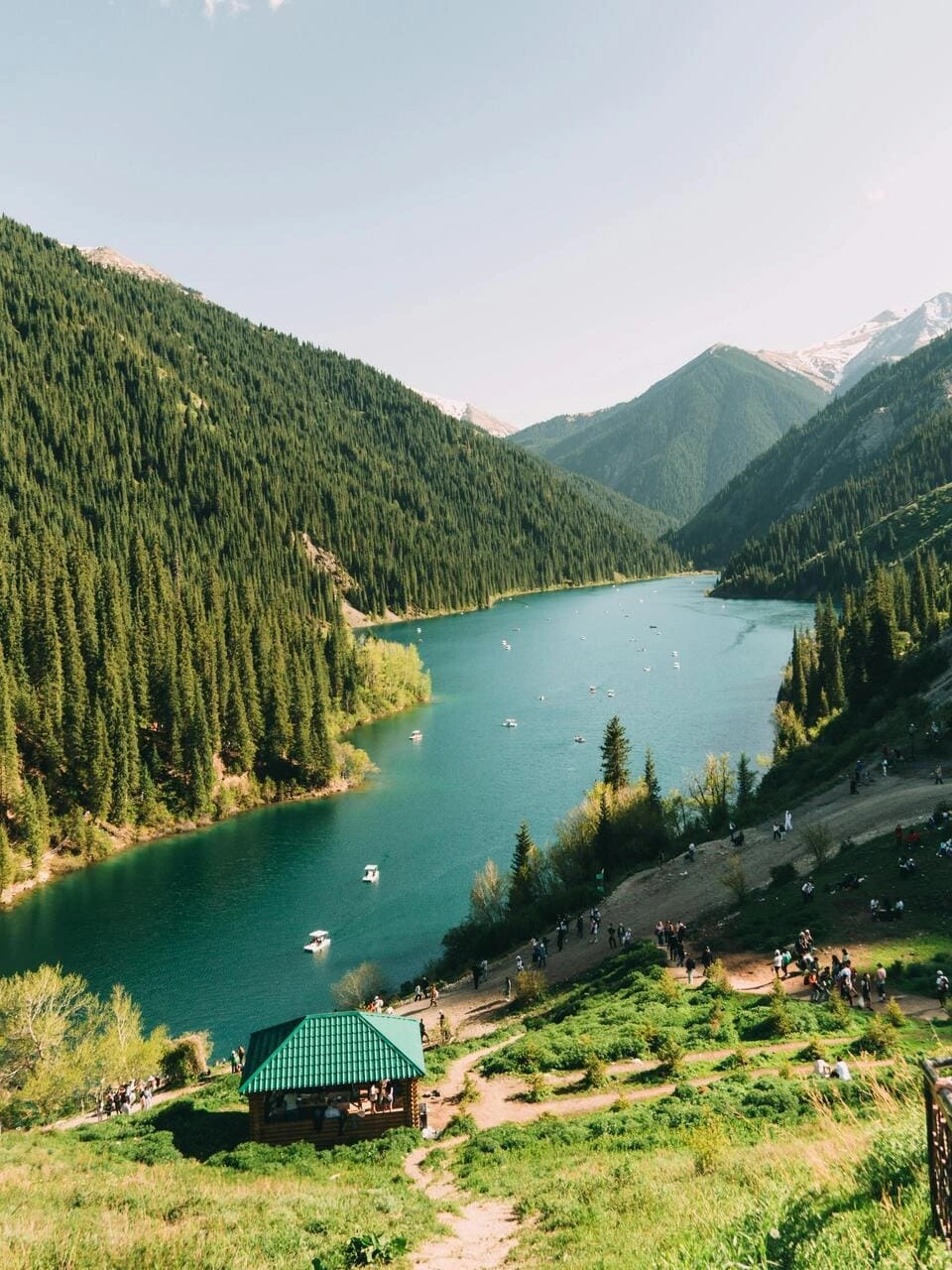 Kolsai Lake with small boats and visitors along the trail