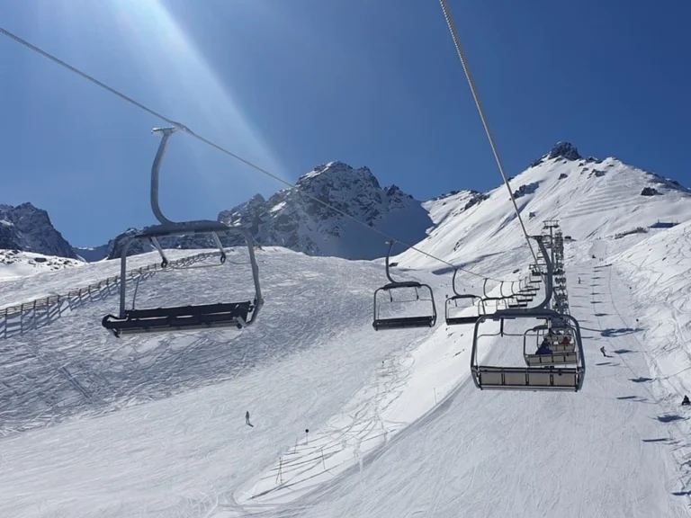 Ski lift going up the mountain at Shymbulak on a sunny winter day
