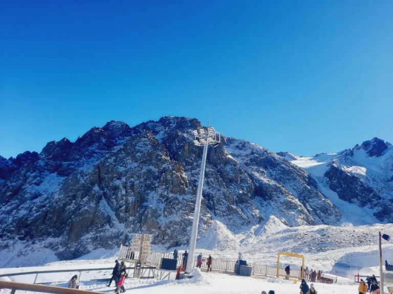 Skiers and snowy rocky peaks at Shymbulak ski resort, Kazakhstan