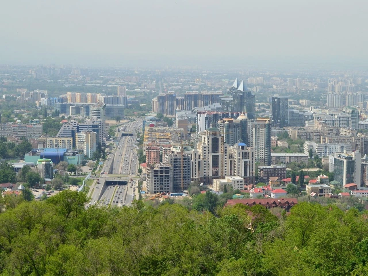 Panoramic view of Almaty city skyline with the snow-capped Tian Shan mountains in the background.
