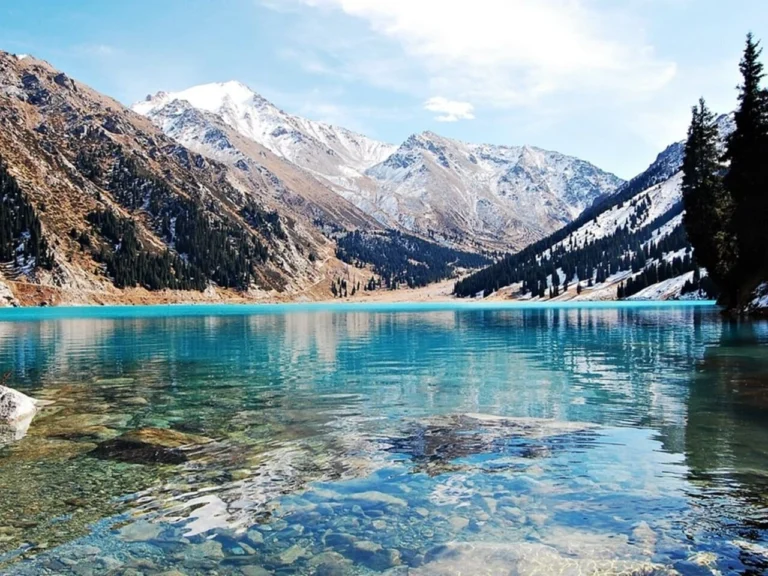 Crystal-clear turquoise water of Big Almaty Lake with mountains in the background.