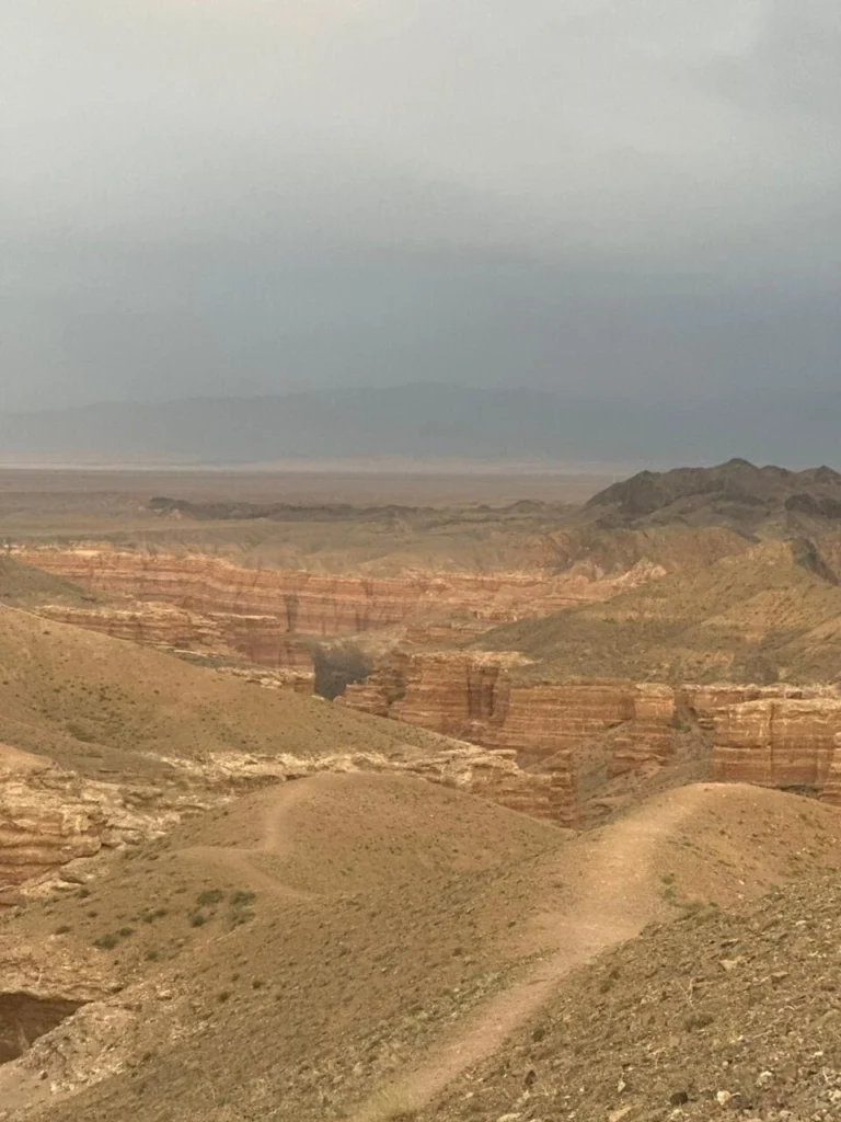 Sunrise over Charyn Canyon illuminating the orange and red sandstone formations.