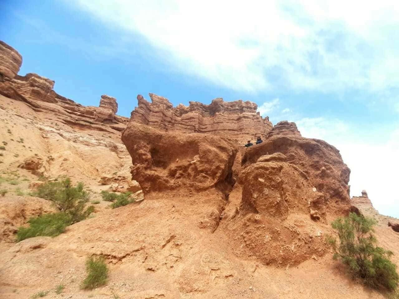 Travelers enjoying picnic lunch with panoramic views of Charyn Canyon cliffs.