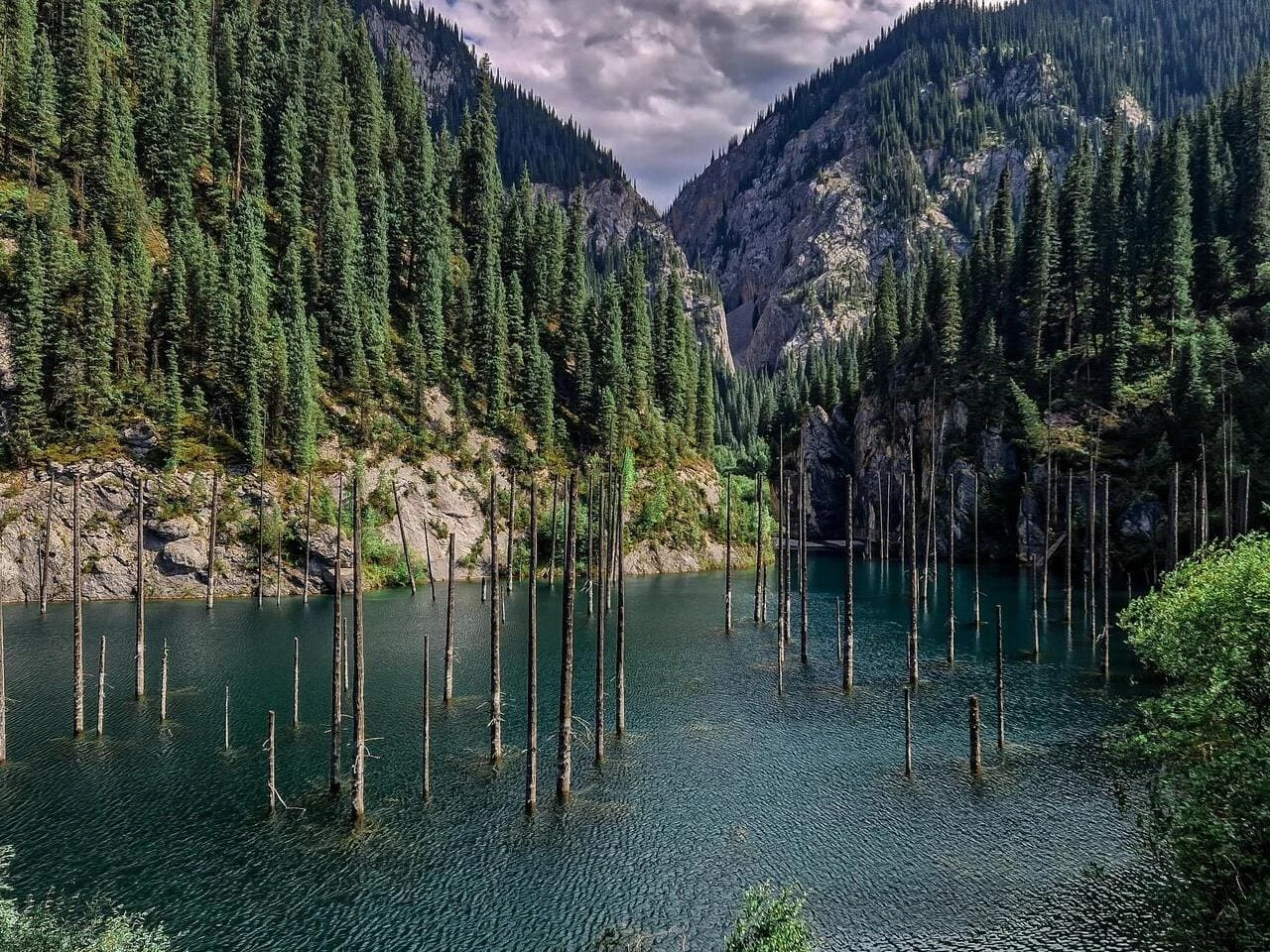 Backpackers camping near Kaindy Lake surrounded by natural mountain beauty and fresh air.