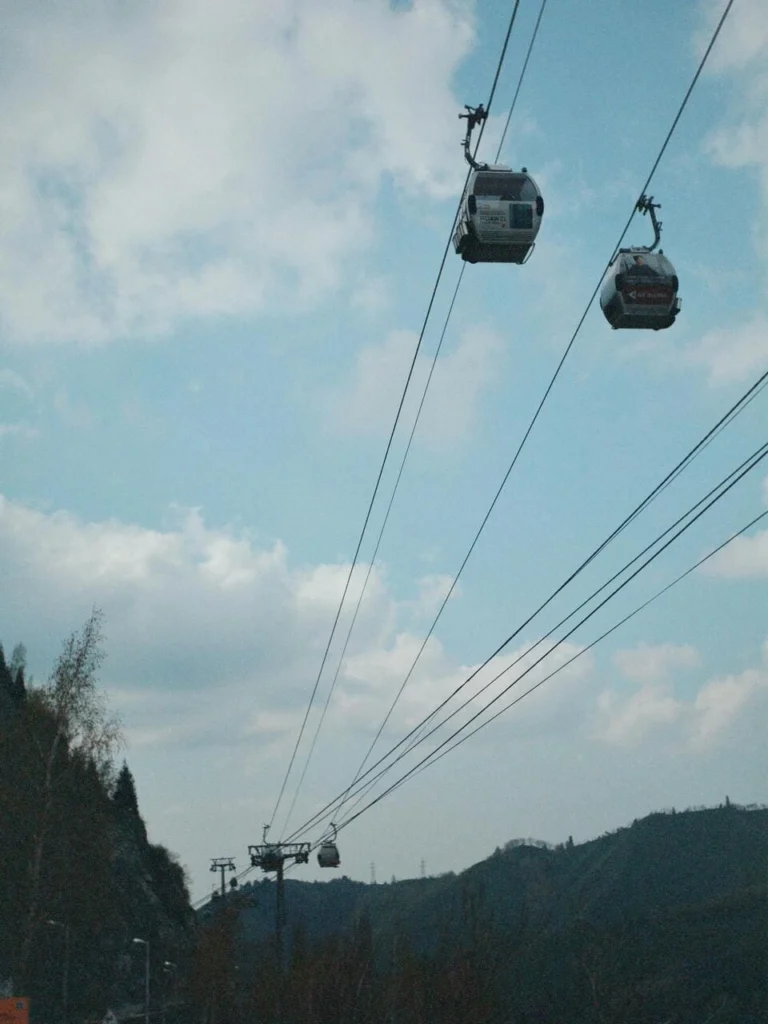 Cable cars ascending Kok Tobe Mountain in Almaty with scenic hills in the background