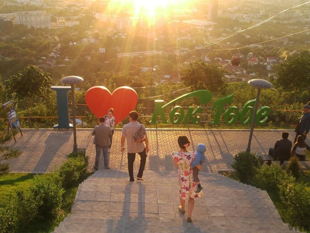 Tourists enjoying the sunset view and “I Love Kok Tobe” sign at the Kok Tobe viewpoint in Almaty