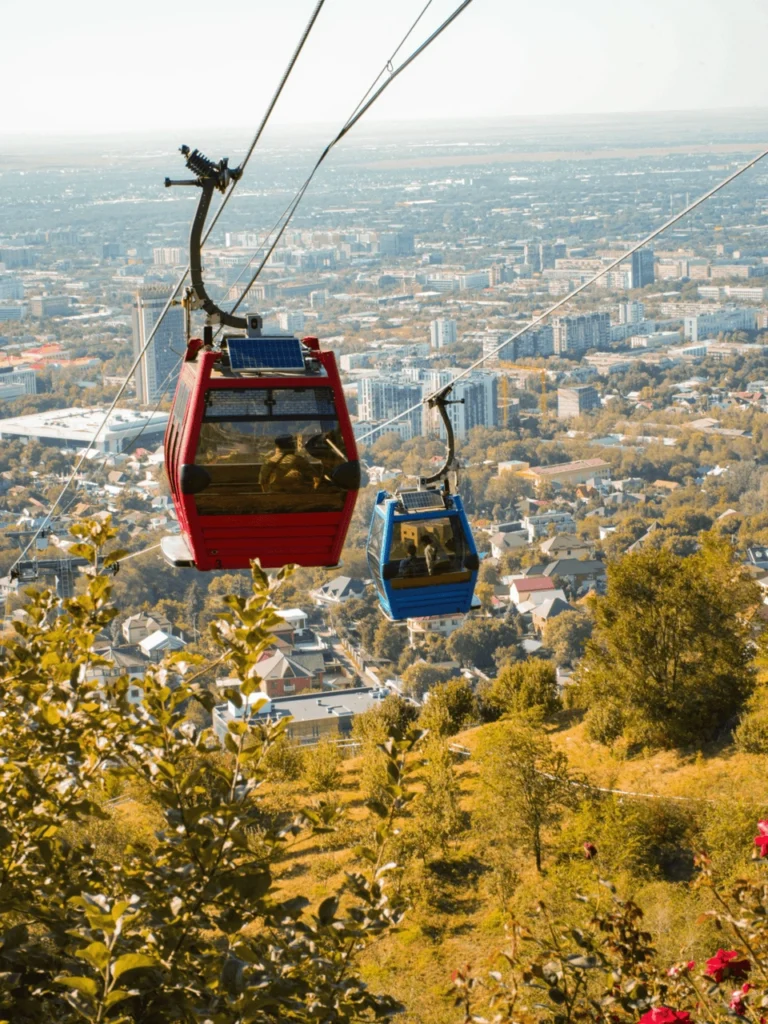 Cable cars moving above Almaty city skyline on the way to Kok Tobe Hill