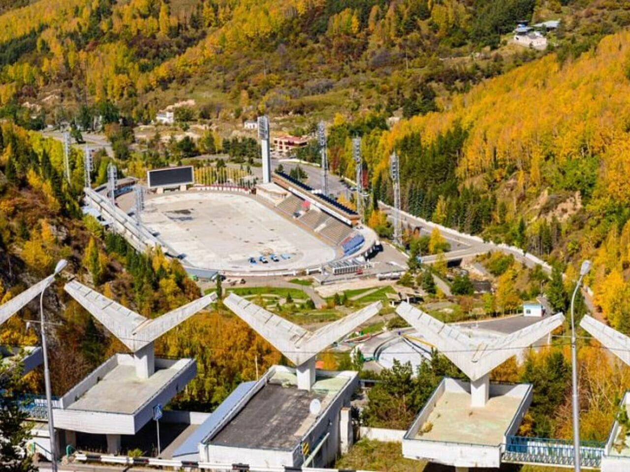 Aerial view of the Medeo skating rink surrounded by autumn forest in Almaty.